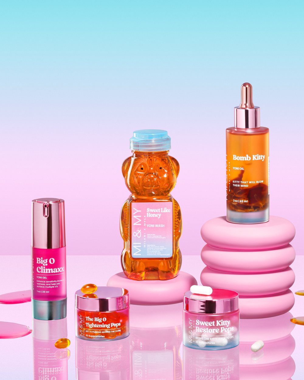 Big O Climaxx Yoni Gel, The Big O Tightening Pops, Sweet Like Honey Yoni Wash, Sweet Kitty Restore Pops, and Bomb Kitty Yoni Oil styled on pink pedestals