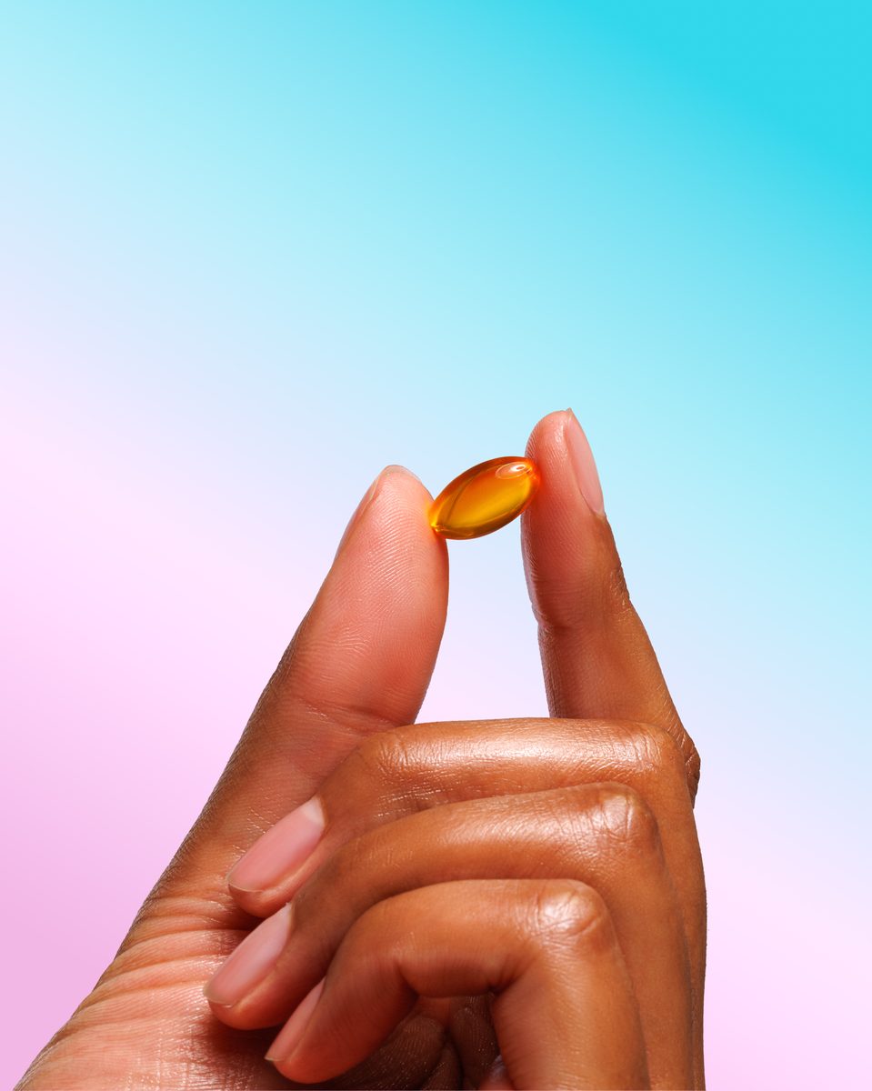 Model holding a single golden softgel capsule